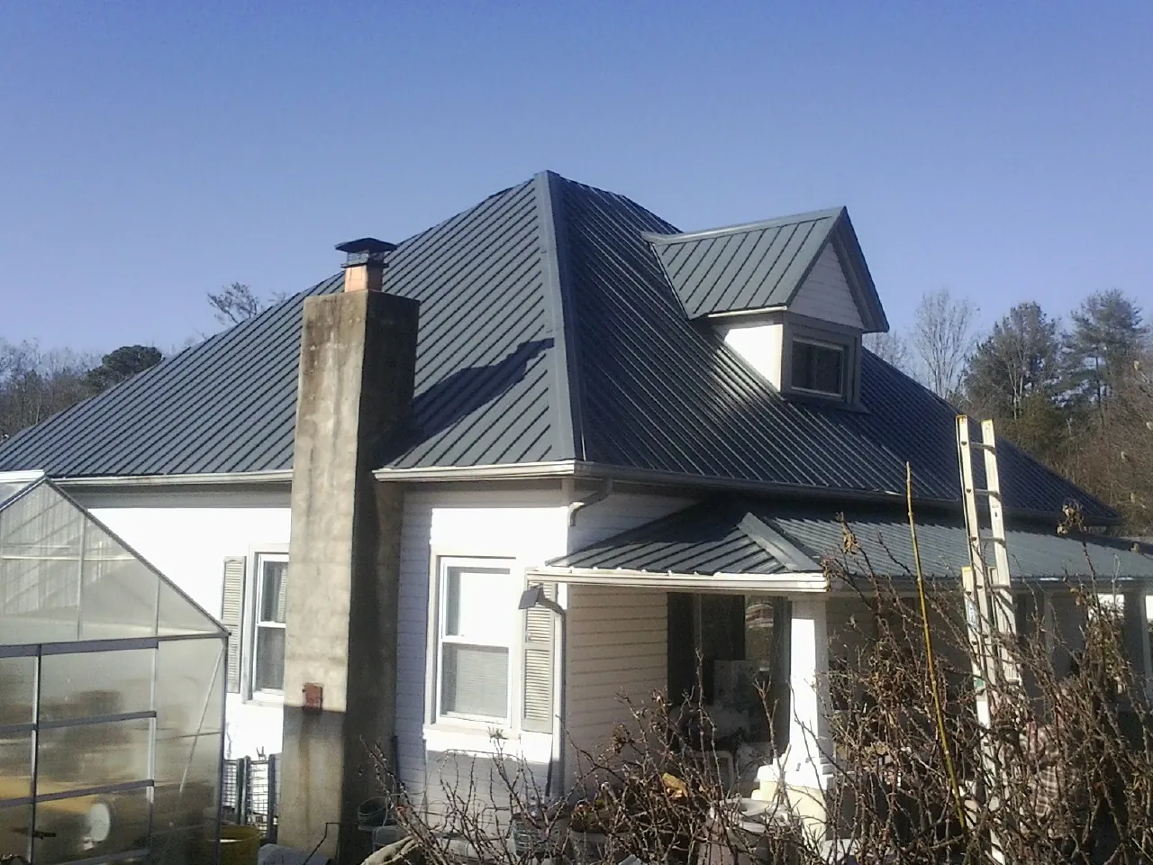 Dark blue standing seam metal roof on a white farmhouse with dormer — Slate & Tile Roof Repair by Roofing Brothers in Mokelumne Hill