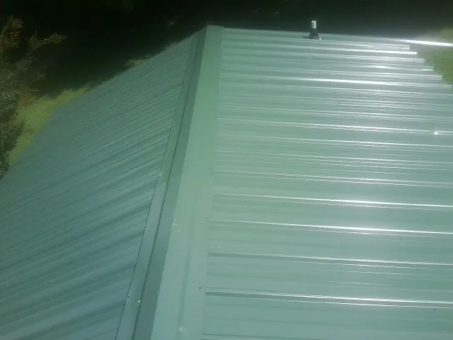 New green metal panels meeting at the ridge of a roof — Flat Roof Repair work by our crew in Mokelumne Hill