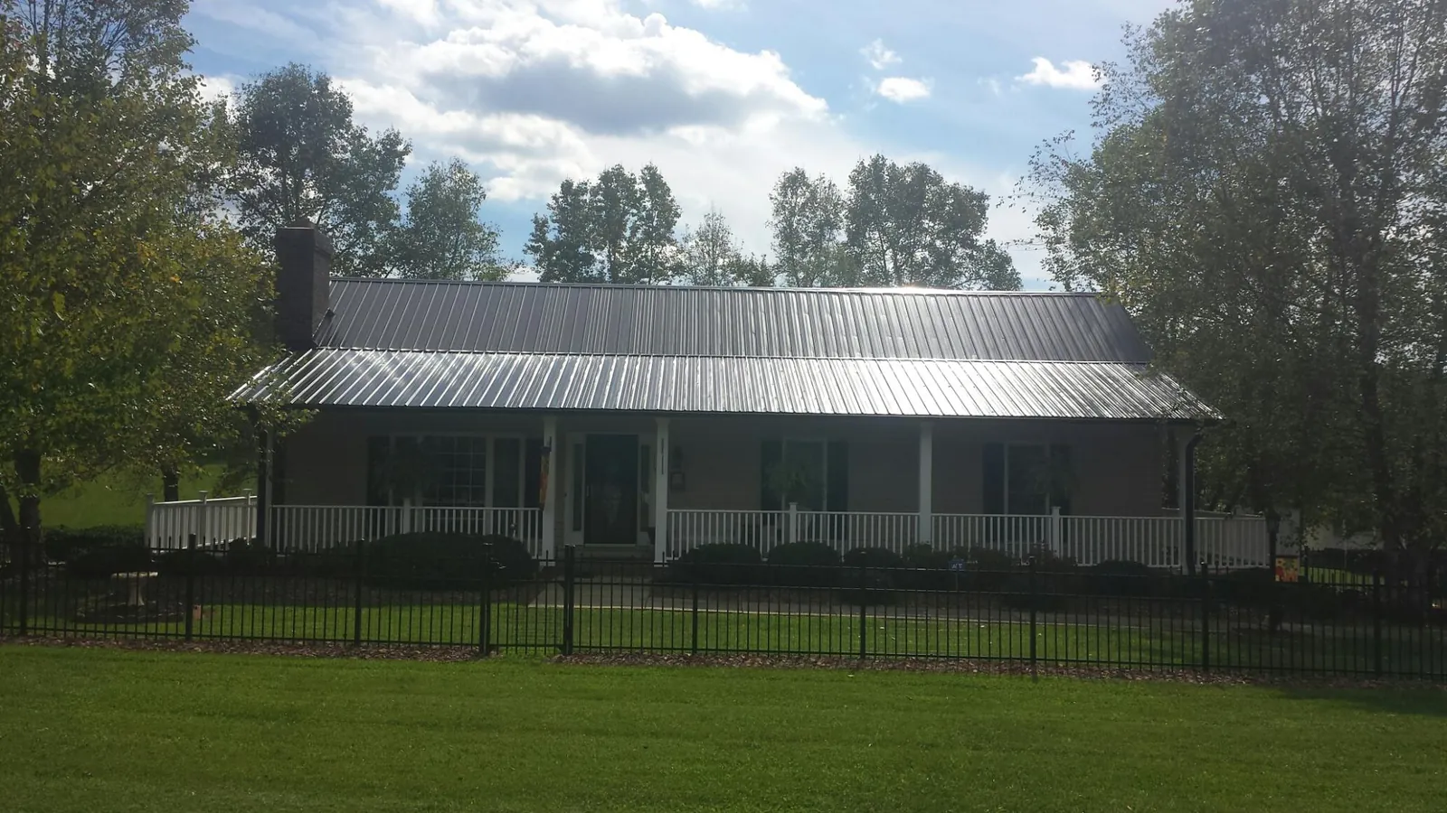 Gray metal roof on a brick ranch with a full width front porch — Gutter Guard Installation work by our crew in Mokelumne Hill