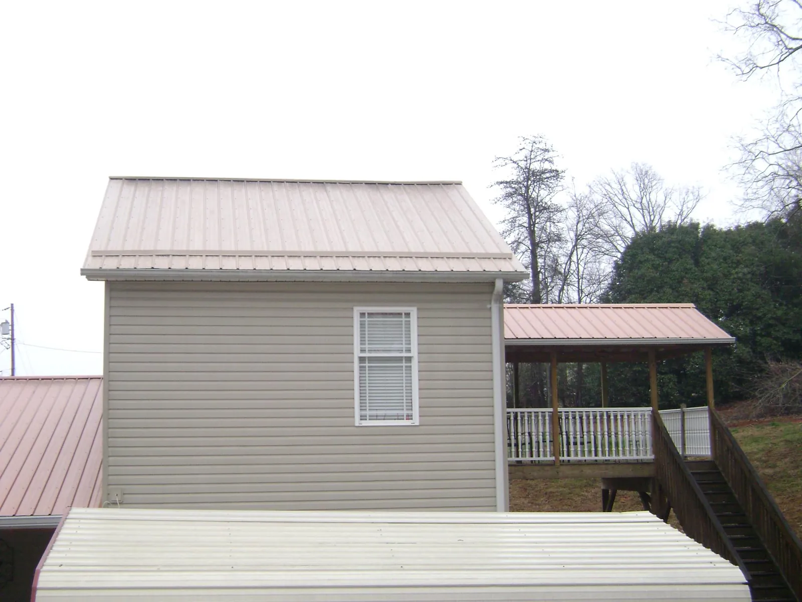 Tan metal roofs on a two story addition and attached porch, from a Roof Replacement job in Mokelumne Hill