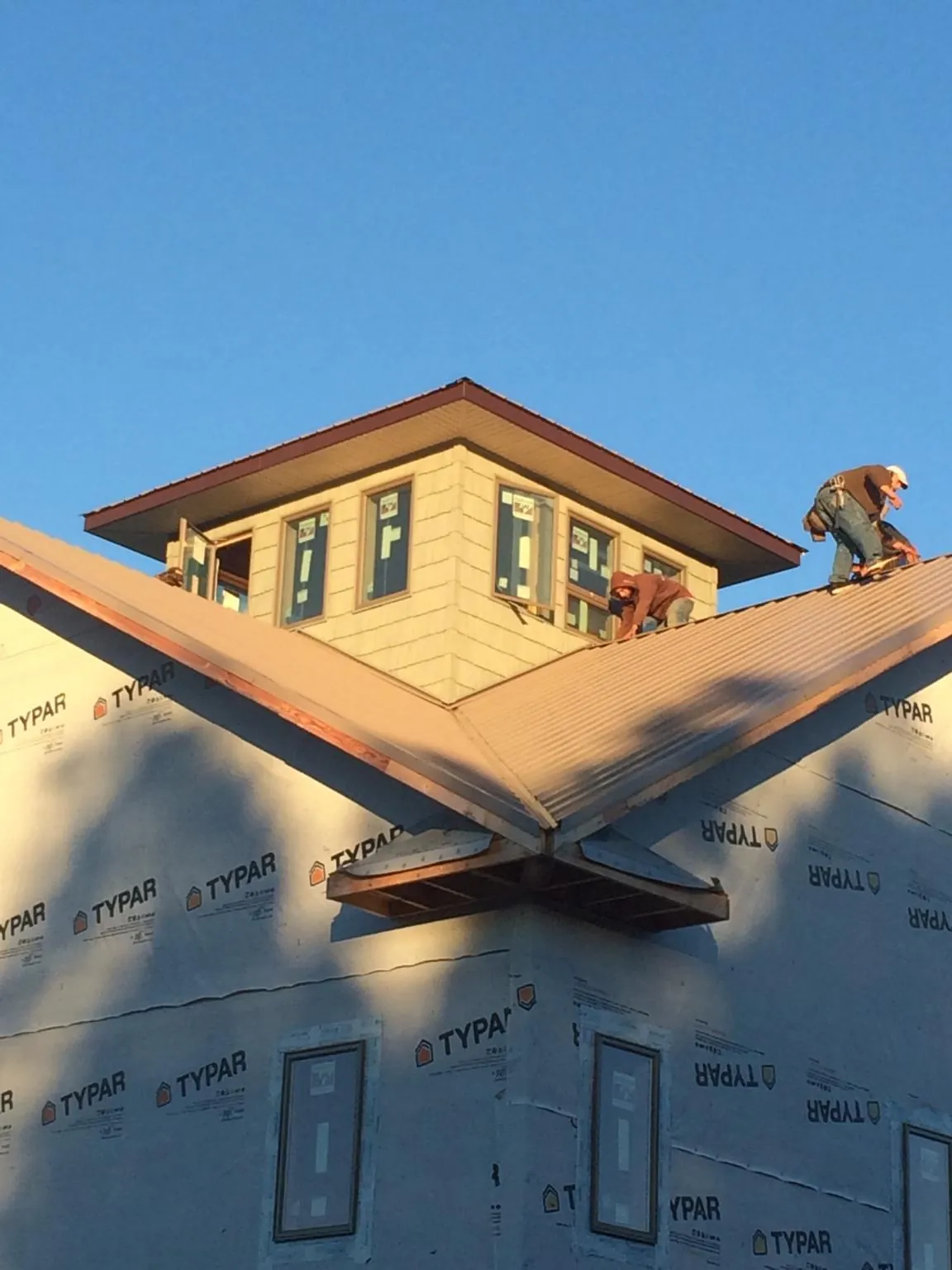 Roofers working around a rooftop cupola on a new metal roof at sunset — Roof Waterproofing in Mokelumne Hill by Roofing Brothers